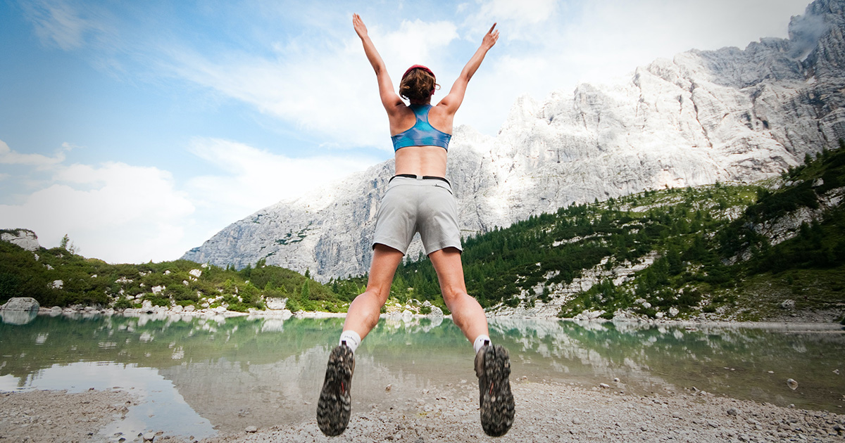 A woman in the mountains jumping into the air